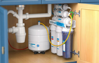 Under-sink water filtration system featuring multiple filter cartridges, a pressurized storage tank, and integrated plumbing beneath a blue kitchen cabinet.